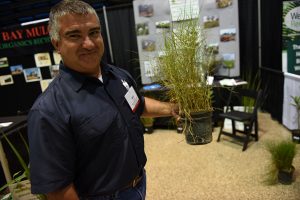 Mike Sobba, manages Martin County Farms native plant nursery for Aquatic Vegetation Control. Here, with a grass used for restoration.